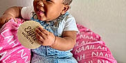 Naailah joined the competition — help win amazing prizes! baby, child, girl, smiling, denim_dress, pink_bows, cushion, personalized_blanket, toy, unicorn, wooden_sign, eight_months, sitting, happy, indoors, bracelet, white_shirt, cozy, portrait, cute