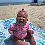 baby, smiling, beach, towel, sand, umbrella, sunny, headband, pink, floral, child, happy, summer, outdoor, feet, sitting, ocean, blue, vacation, person