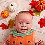 Daisy joined the competition — help win amazing prizes! autumn_leaves, baby, background, child, costume, cute, decorative_pumpkins, face, fall_theme, green_collar, happy, holiday, indoor, infant, orange, portrait, pumpkin_outfit, seasonal, smiling, striped_shirt
