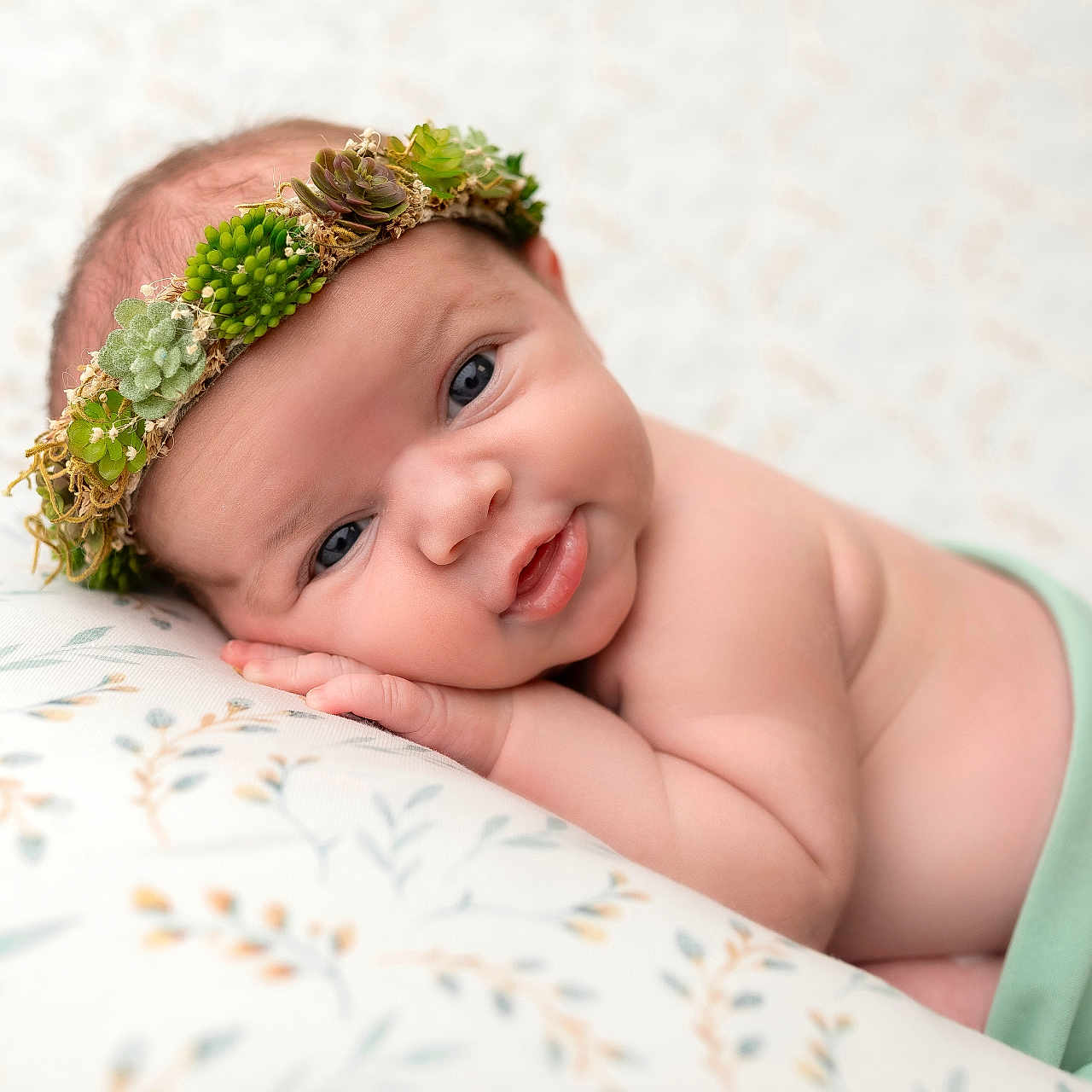 Fern joined the competition — help win amazing prizes! baby, blanket, child, closeup, crown, cute, expression, face, green_cloth, hand, headwear, indoors, infant, lying_down, newborn, pattern, portrait, skin, soft_light, succulent