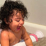 Elianne is registered to the contest to win money with this photo: toddler, child, bath, water, curly_hair, wet, happy, smiling, playing, bathtub, skin, splashing, fun, indoor, person, cute, joyful, young_child, bath_toy, closeup