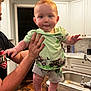 Chase joined the competition — help win amazing prizes! baby, child, person, indoor, kitchen, counter, sink, cabinet, shirt, shorts, hand, face, legs, feet, hair, mohaawk, expression, curious, adult, holding
