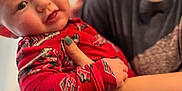 Chase is registered to the contest to win money with this photo: baby, child, person, indoor, holding, pajamas, red_clothing, smile, face, adult, hand, arm, curious, closeup, portrait, young_child, skin, fingernails, blurred_background, casual