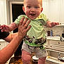 Chase is registered to the contest to win money with this photo: baby, child, smiling, happy, person, kitchen, cabinet, sink, countertop, clothing, shorts, tshirt, hand, table, wood, indoor, facial_expression, hair, holding, playful