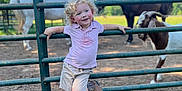 Ryder joined the competition — help win amazing prizes! child, toddler, curly_hair, cowboy_boots, fence, pasture, horses, goat, grass, sunny, outdoor, nature, animal, farm, smiling, casual_clothing, shorts, shirt, daylight, happy