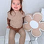 Camélia participe au concours pour gagner de l'argent avec cette photo : child, toddler, smiling, sitting, indoor, beige, cushion, flower_pillow, sweater, tights, boots, portrait, happy, hair, face, legs, tile_floor, seat, home, soft_texture