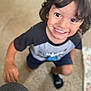 child, smiling, indoor, carpet, blurry, person, young_child, toddler, shorts, tshirt, black_sock, hair, happy, face, hand, floor, blanket, home, casual, playful