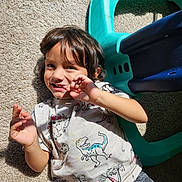 Glenn is registered to the contest to win money with this photo: child, toddler, carpet, sunlight, dinosaur_shirt, playful, smile, toy, plastic_toy, indoor, casual_clothing, short_hair, person, happy, cute, young_child, sitting, hand_gesture, face, home