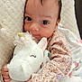 baby, infant, child, plush_toy, unicorn, blanket, floral_pattern, pink_clothing, cute, smiling, soft_texture, closeup, indoors, person, portrait, toddler, cozy, sleepytime, hand, face