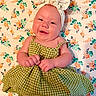 baby, smiling, green_dress, headband, bow, floral_pattern, blanket, cute, infant, portrait, happy, child, lying_down, cheerful, skin, person, indoors, closeup, baby_girl, fashion