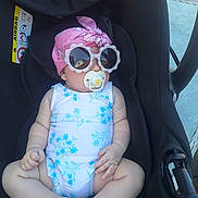 Bella Marie is registered to the contest to win money with this photo: baby, car_seat, sunglasses, pacifier, headscarf, pink, blue, white, floral_pattern, infant, child, outdoor, sunny, cute, relaxed, clothing, seat, accessory, portrait, person