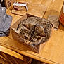 Olga is registered to the contest to win money with this photo: cat, tabby, cardboard_box, table, wooden_table, soda_cans, metal_bowl, snack_box, chair, floor, clutter, indoor, pet, animal, whiskers, fur, domestic_cat, relaxed, feline, household