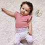 baby, infant, child, pink_clothing, curly_hair, milestone_marker, 5_months, white_rug, soft_texture, lying_down, cute, sock, patterned_pants, portrait, indoors, smiling, skin, person, young_child, relaxed