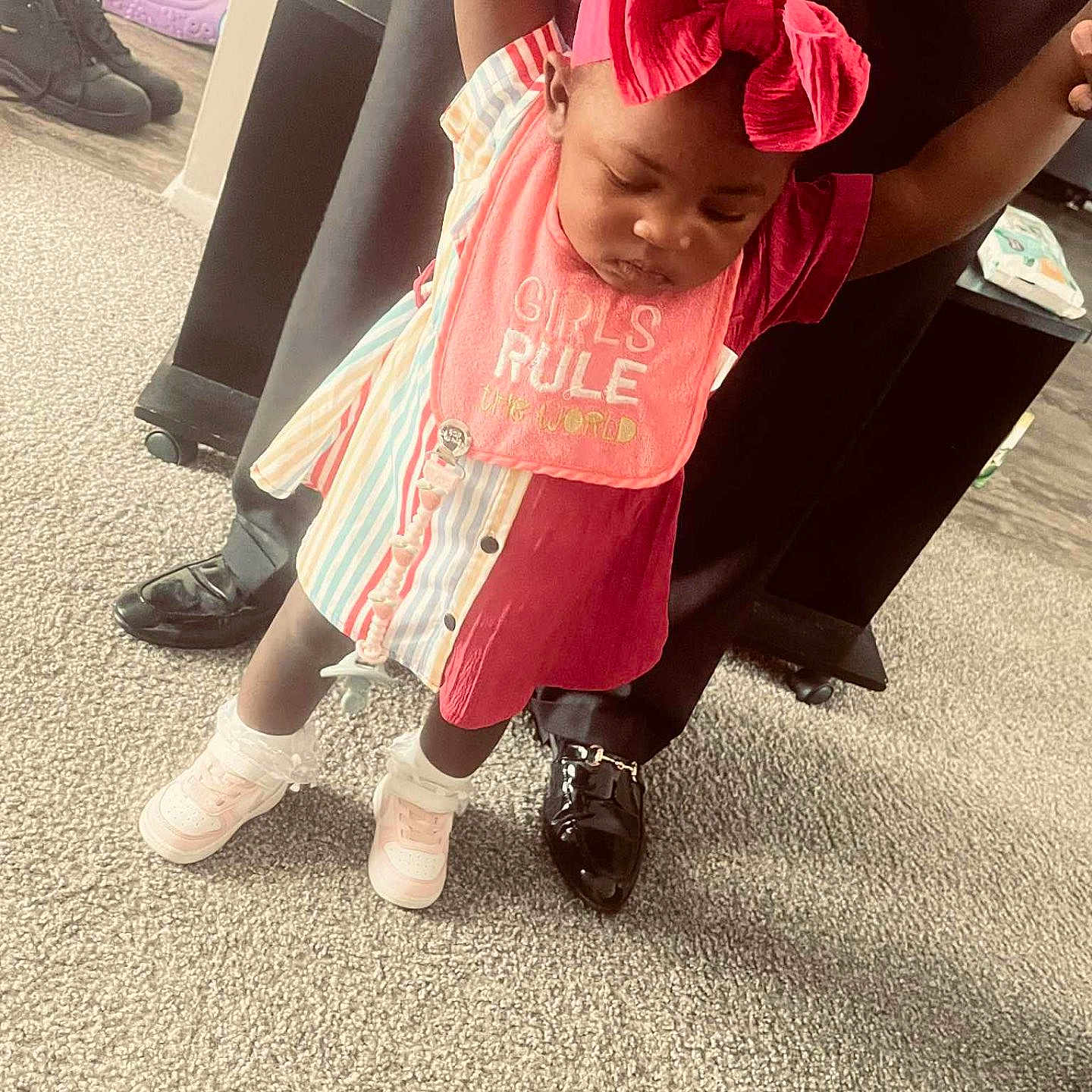 Makayla joined the competition — help win amazing prizes! adult_hands, baby, carpet, child, colorful_clothing, cute, fashion, floor, holding_hands, home, indoor, learning_to_walk, person, pink_bib, playful, red_bow, shoes, standing, support, toddler