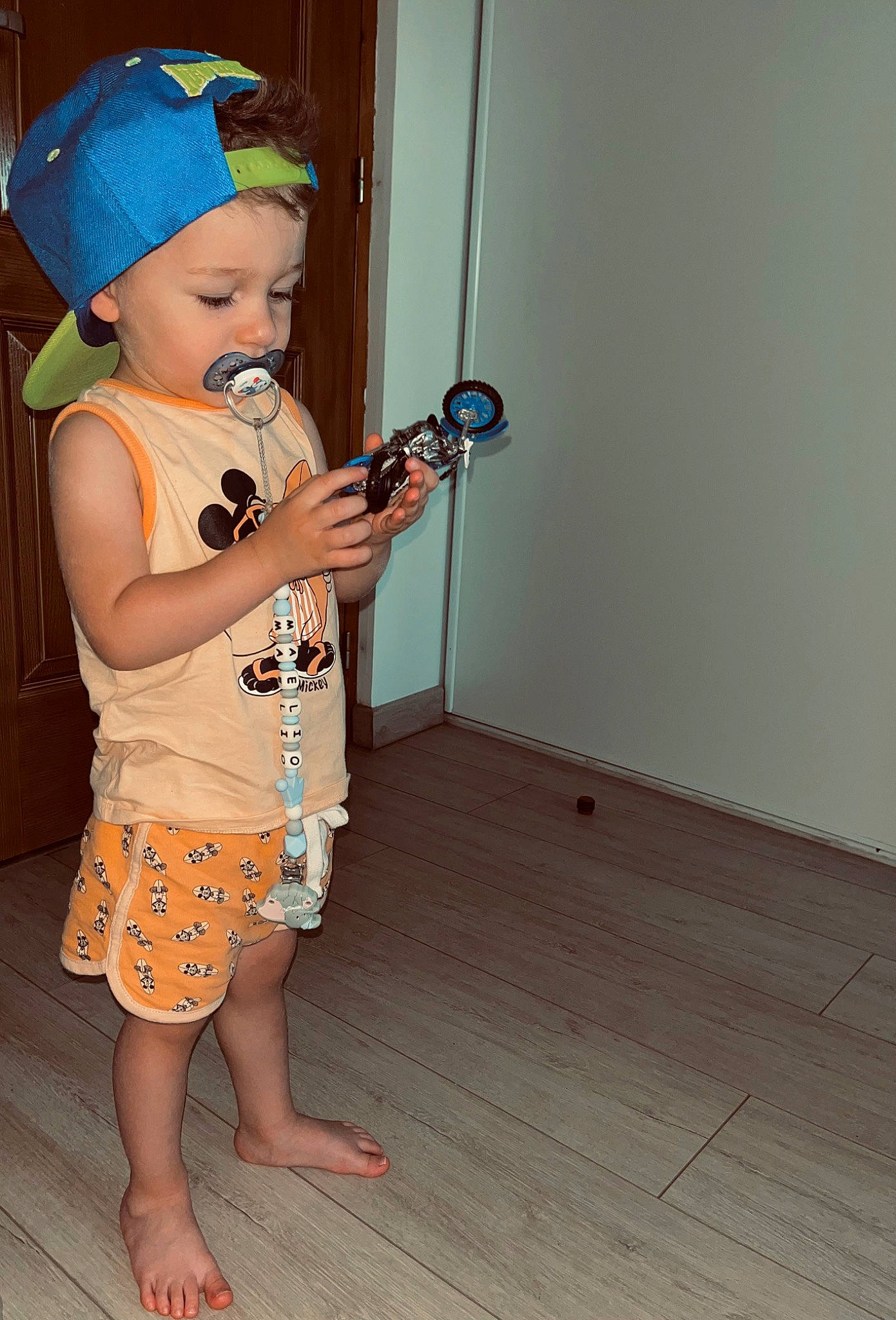 Maëlio a rejoint le concours — aidez-le/la à gagner de superbes lots ! baby, baby_toddler_clothing, barefoot, baseball_cap, cap, child, costume_hat, door, electric_blue, flooring, foot, fun, hardwood, hat, headwear, pattern, person, sleeve, t_shirt, toddler
