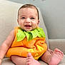baby, infant, pumpkin_costume, smiling, happy, cute, child, feet, orange, green, clothing, costume, portrait, indoors, soft_surface, head, face, eyes, mouth, skin