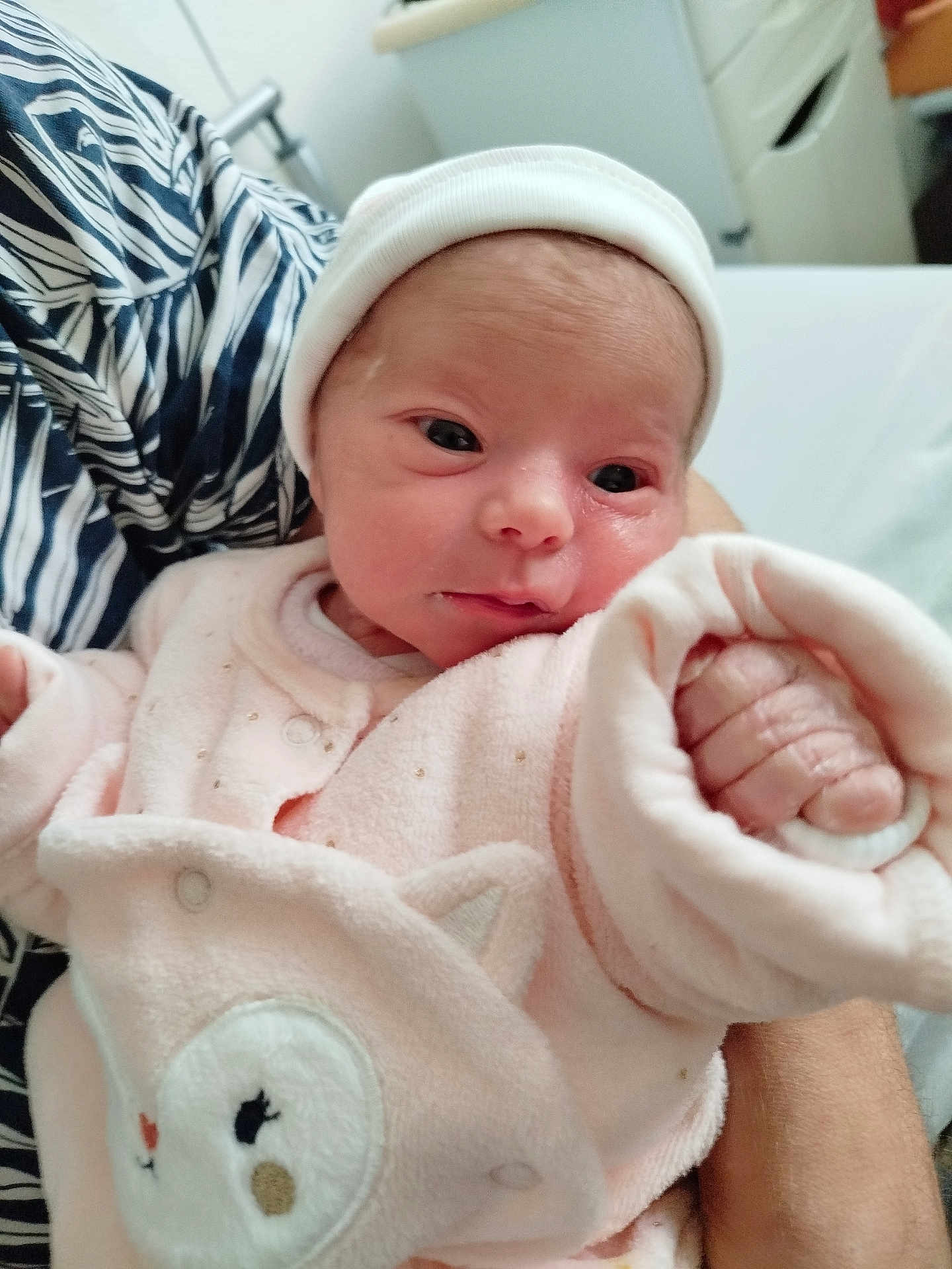 Syléa a rejoint le concours — aidez-le/la à gagner de superbes lots ! newborn, baby, infant, pink_clothing, hat, hand, face, person, indoor, cute, soft, cozy, sleepwear, wrapped, child, human, small, newborn_baby, closeup, warm