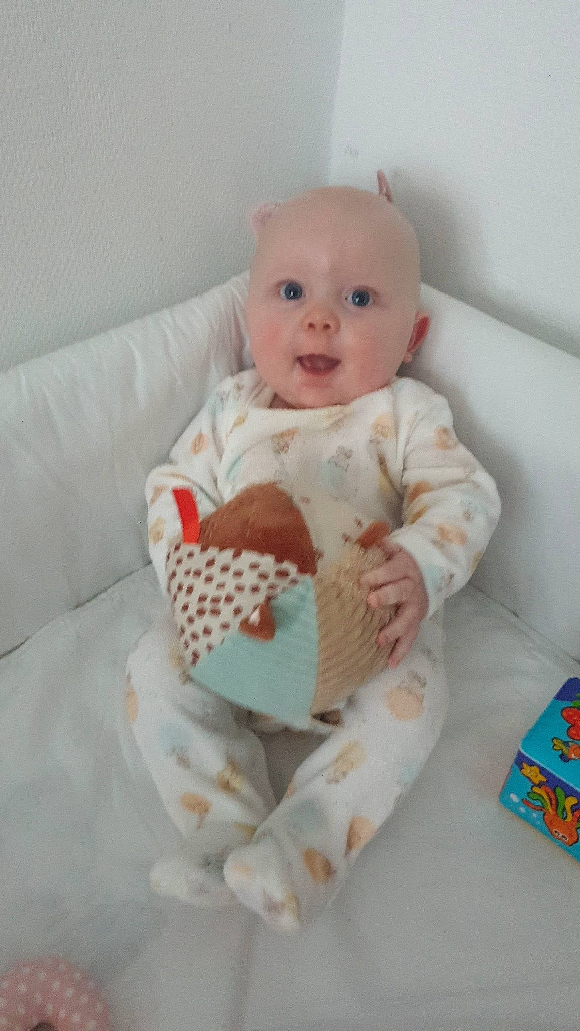 Olivia a rejoint le concours — aidez-le/la à gagner de superbes lots ! baby, baby_products, baby_safety, baby_sleeping, baby_toddler_clothing, baby_toys, cheek, child, comfort, couch, eye, foot, head, linens, pattern, person, room, sitting, sleeve, smile