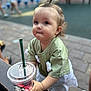 Erika is registered to the contest to win money with this photo: toddler, child, cup, drink, straw, starbucks, green_shirt, outdoor, bench, curly_hair, face, eyes, hand, person, sidewalk, people, casual_clothing, daylight, portrait, cute
