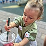 Erika is registered to the contest to win money with this photo: toddler, child, drink, straw, starbucks, cup, outdoor, concentration, hand, hair, green_shirt, flower_patch, pavement, table, person, cute, daylight, young_child, casual_clothing, playful
