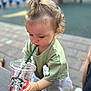 toddler, child, drinking, strawberry_drink, starbucks_cup, plastic_cup, straw, green_shirt, flower_patch, outdoor, table, pavement, hand, hair, pony_tail, person, summer, refreshment, drink, cute