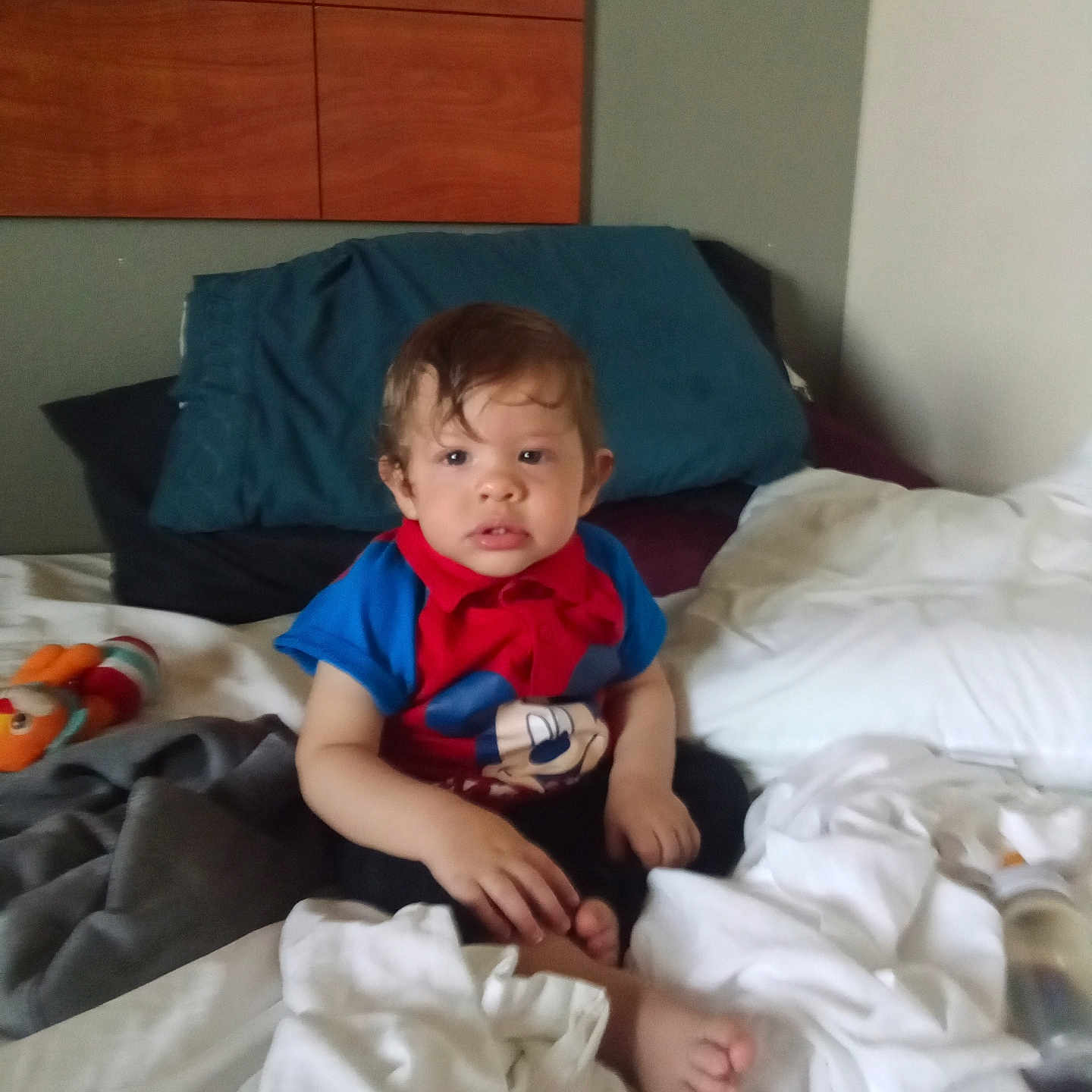 Bobby is registered to the contest to win money with this photo: bed, blanket, casual, child, clothing, comfort, curious, face, feet, furniture, hair, home, indoor, person, pillow, room, shirt, sitting, toy, young