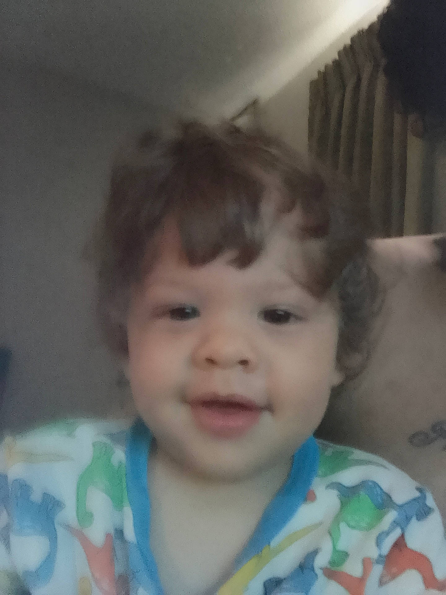 baby, child, clothing, curly_hair, curtains, cute, dinosaur_pattern, expression, face, hair, head, indoors, light, pajamas, person, portrait, room, smile, toddler, young_child