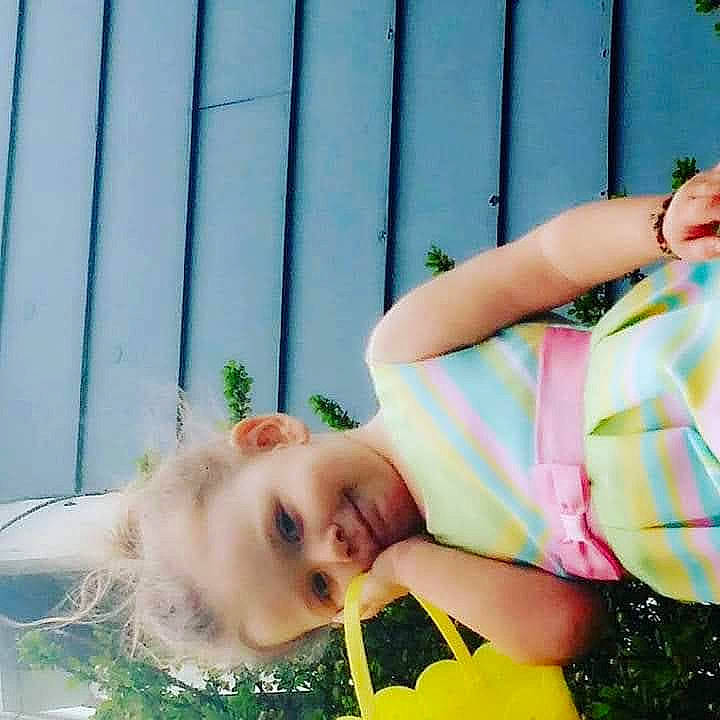 Gabby is registered to the contest to win money with this photo: brown_hair, child, fashion_accessory, fence, fun, grass, hand, happy, human_leg, leisure, pattern, people_in_nature, person, photo_shoot, photograph, plant, portrait_photography, sitting, smile, summer