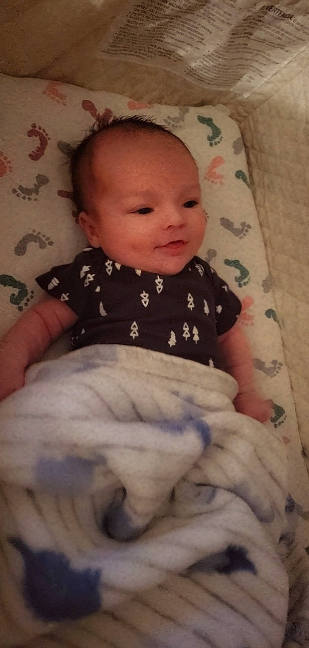 Jose is registered to the contest to win money with this photo: baby, baby_products, baby_toddler_clothing, cheek, child, chin, comfort, eye, face, iris, linens, lip, nose, pattern, person, room, sitting, skin, sleeve, textile