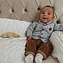 Ibrahim participe au concours pour gagner de l'argent avec cette photo : baby, infant, smiling, couch, pillow, clothing, corduroy, shirt, button_up, milestone, wooden_sign, face, happy, sitting, indoor, soft_lighting, head, feet, white_socks, tufted_couch