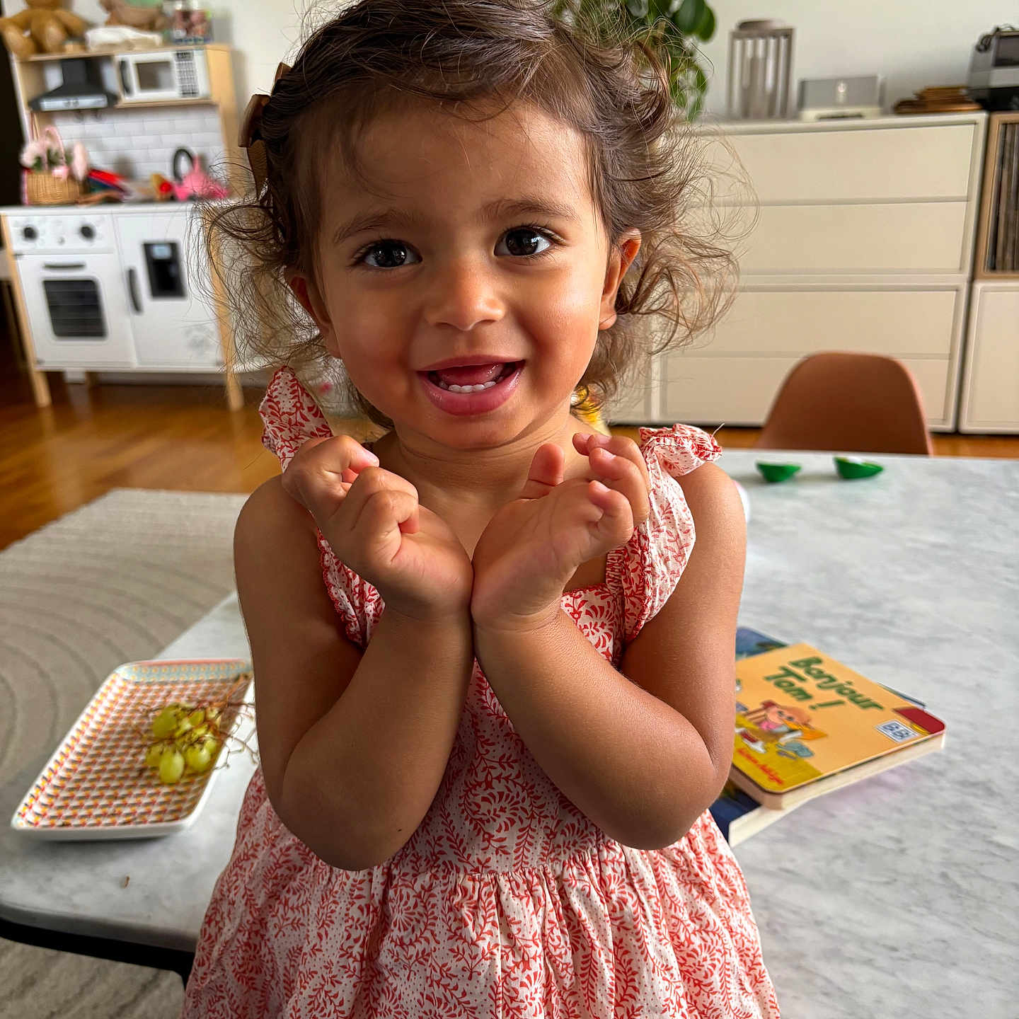 Ezzah participe au concours pour gagner de l'argent avec cette photo : book, chair, child, curly_hair, dress, face, floor, furniture, grapes, hands, happy, home, indoor, living_room, person, plant, smiling, table, toddler, toys
