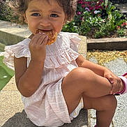 Ezzah participe au concours pour gagner de l'argent avec cette photo : child, girl, curly_hair, pink_dress, sandals, pastry, outdoor, sunlight, flowers, greenery, sitting, cross_legged, face, food, nature, daylight, garden, cute, casual, summer