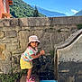Ezzah participe au concours pour gagner de l'argent avec cette photo : toddler, child, water, fountain, stone_wall, mountains, outdoor, blue_sky, hat, yellow_skirt, pink_sandals, plants, sunlight, nature, summer, play, portrait, casual_clothing, daytime, young_child