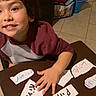 brown_hair, casual, child, dresser, education, flashcards, handwritten, happy, home, indoor, learning, long_sleeve_shirt, person, playful, smiling, storage_bin, table, tile_floor, writing, young