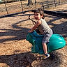 bench, child, daytime, fence, frog_toy, fun, happy, nature, outdoor, park, playground, recreation, shorts, smiling, sneakers, spring_ride, sunny, tank_top, wood_chips, young
