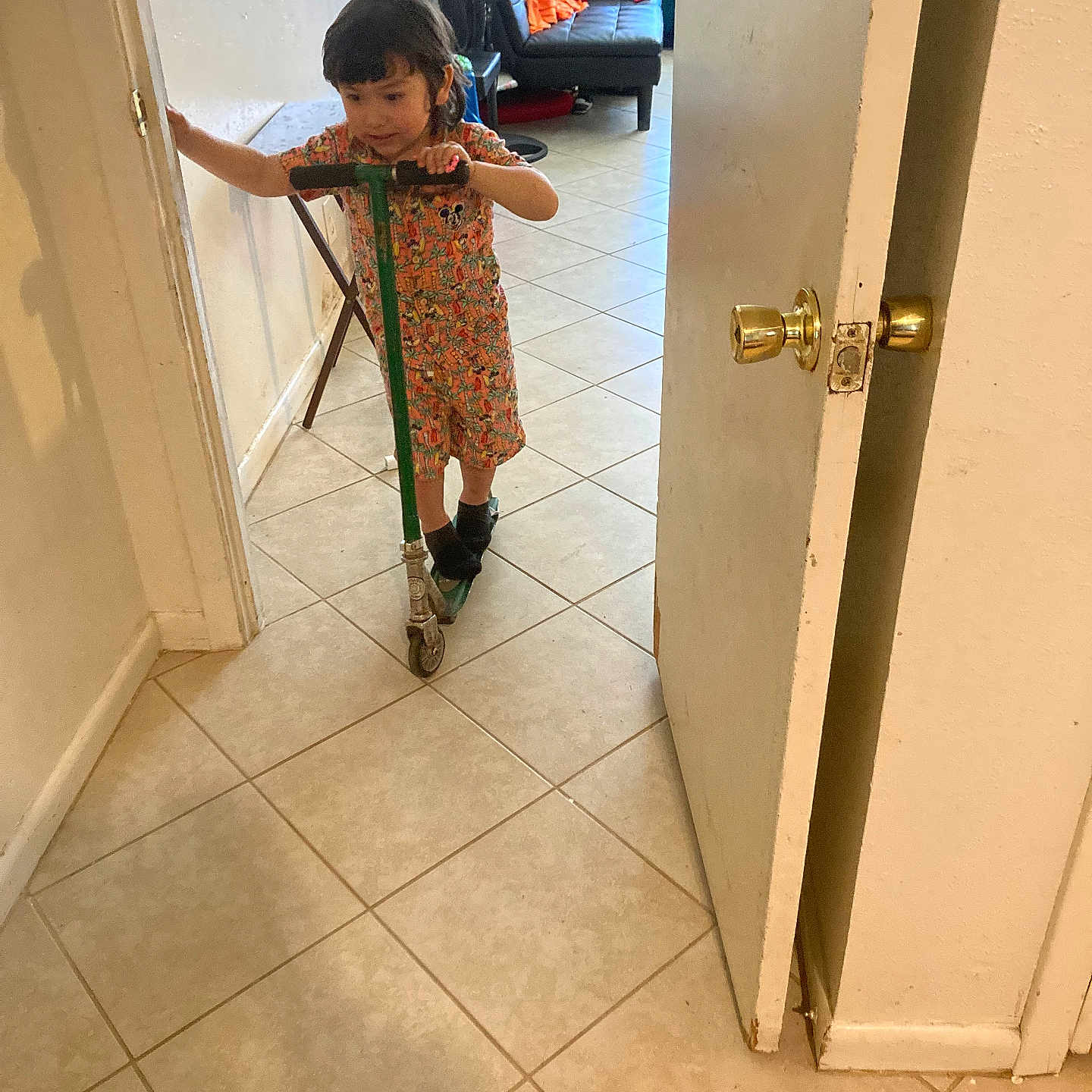 Eli joined the competition — help win amazing prizes! child, scooter, indoor, tile_floor, door, couch, clothing, hand, wall, shadow, person, furniture, living_room, kid, floor, door_handle, casual, home, colorful_outfit, young