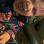 casual_clothing, child, couch, cozy, face, fire_truck_pattern, fun, hand, happy, headphones, home, indoor, leather, pajamas, person, playful, sitting, smiling, tongue_out, young