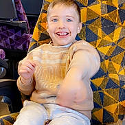 Mason joined the competition — help win amazing prizes! child, smiling, seat, patterned_fabric, yellow, blue, purple_seats, window, snack, clothing, sweater, pants, indoor, public_transport, happy, motion_blur, person, young_child, food, bag