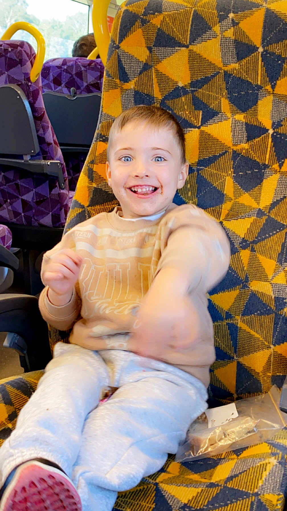 Mason joined the competition — help win amazing prizes! child, smiling, seat, patterned_fabric, yellow, blue, purple_seats, window, snack, clothing, sweater, pants, indoor, public_transport, happy, motion_blur, person, young_child, food, bag