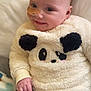 baby, child, smiling, panda_sweater, fluffy_clothing, bandage, nose_bandage, sitting, blanket, indoor, cute, face, happy, infant, black_pants, soft_texture, young_child, portrait, cozy, person