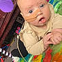 baby, infant, nasal_tube, blue_eyes, toys, play_mat, inflatable_toy, colorful, indoor, child, person, curious, gripping, clothing, floor, carpet, wooden_furniture, plastic_toy, closeup, portrait