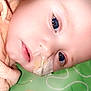 baby, infant, face, blue_eyes, nasal_tube, medical_tape, close_up, lying_down, peach_clothing, child, person, skin, head, expression, healthy, young, cute, indoors, colorful_background, soft_lighting