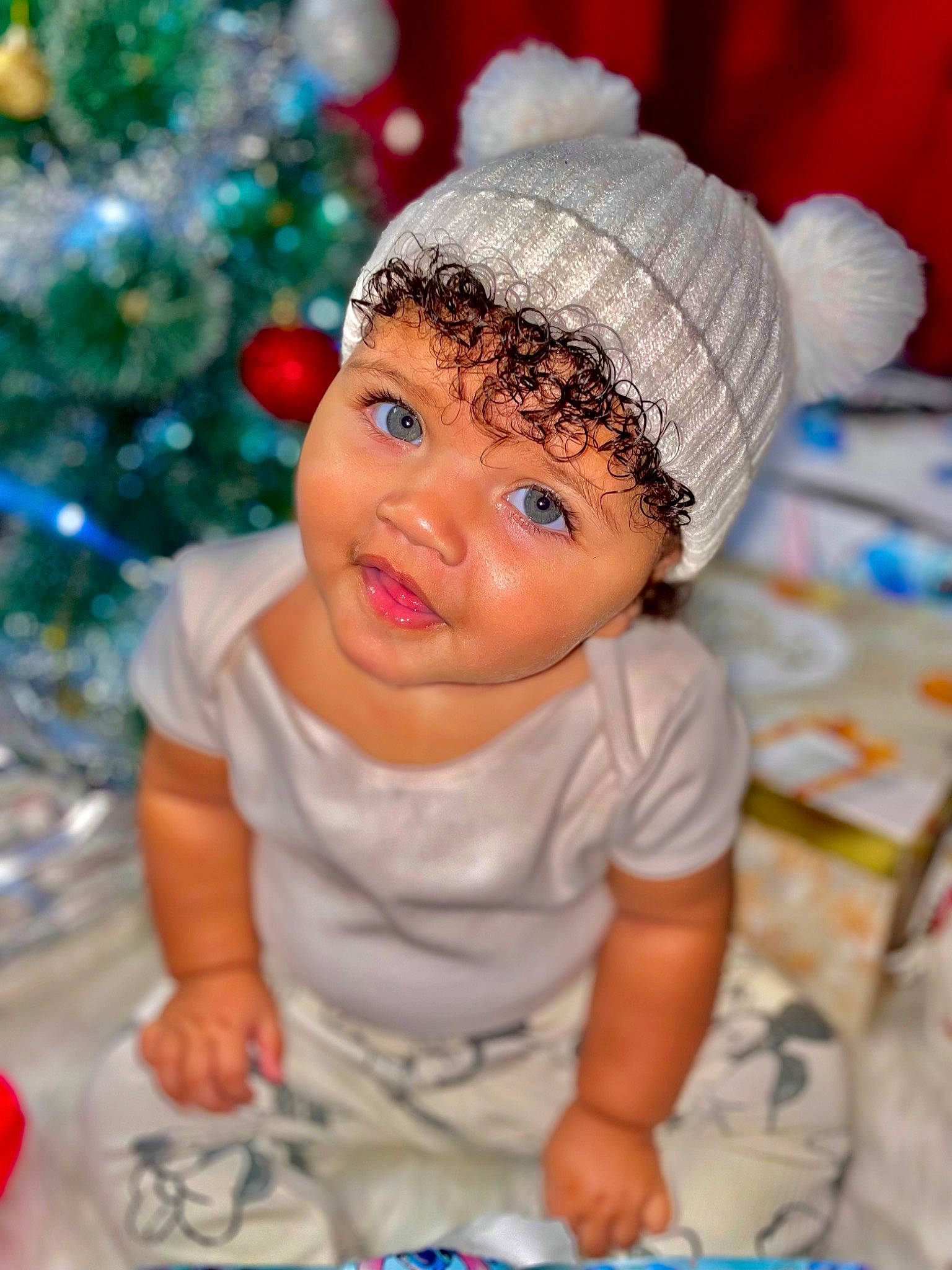 Soraya is registered to the contest to win money with this photo: baby, baby_toddler_clothing, cap, cheek, child, christmas_tree, costume_hat, event, eye, face, facial_expression, fashion_accessory, fun, happy, hat, head, headwear, knit_cap, person, skin