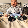 baby, bed, blanket, bottle, child, curious, expression, face, footwear, furniture, head, indoor, infant, pants, person, pillow, plaid_shirt, shoes, sitting, young_child