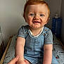 baby, blue_eyes, changing_pad, child, cute, denim_overalls, hand, happy, holding_hand, home, indoor, infant, lotion_bottle, person, portrait, red_hair, sitting, skin, smiling, striped_shirt