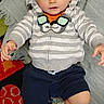 baby, child, striped_hoodie, bowtie, navy_shorts, white_socks, blanket, colorful_rug, indoor, cute, curious, seated, young_child, portrait, soft_lighting, casual_clothing, floor, comfort, happy, infant