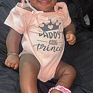 Jaloni is registered to the contest to win money with this photo: baby, infant, smiling, pink_clothing, bow, bracelet, anklet, cute, happy, portrait, child, person, sitting, footwear, accessory, black_background, closeup, skin, face, cute_outfit