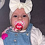 baby, infant, pacifier, denim_overalls, headband, white_bow, cute, child, close_up, sucking, pink, heart_pattern, clothing, person, indoor, hand, face, blue_eyes, button, accessory
