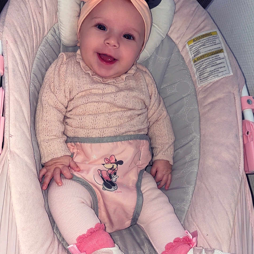 Layna participe au concours pour gagner de l'argent avec cette photo : baby, baby_rocker, bow, child, clothing, cushion, cute, happy, headband, indoor, infant, knit_sweater, minnie_mouse, person, pink, portrait, seat, shoes, smiling, socks