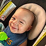 baby, blue_bib, car_seat, child, close_up, comfort, expression, face, green_toy, happy, head, indoor, infant, padded_seat, person, seat_belt, skin, smiling, toy, warning_label